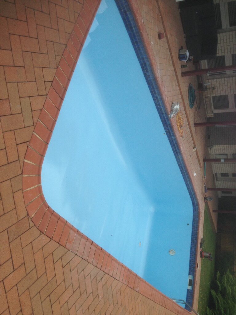 Finished residential pool with brick coping and blue epoxy interior