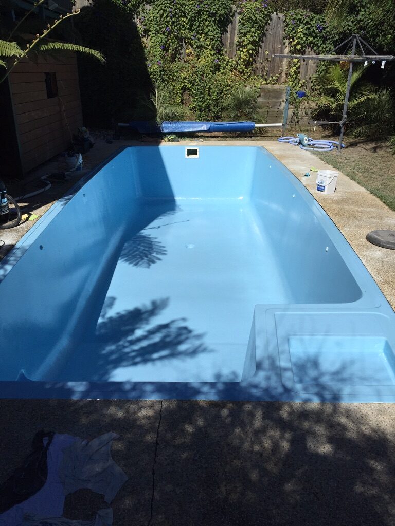 Finished residential pool with new blue epoxy coating, freshly drained