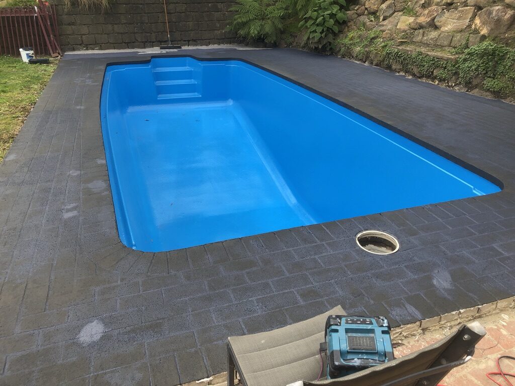 Completed residential fibreglass pool with fresh blue epoxy coating