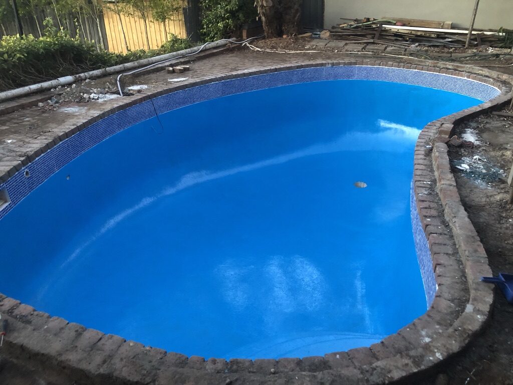 Same kidney-shaped pool freshly finished with vivid blue epoxy coating