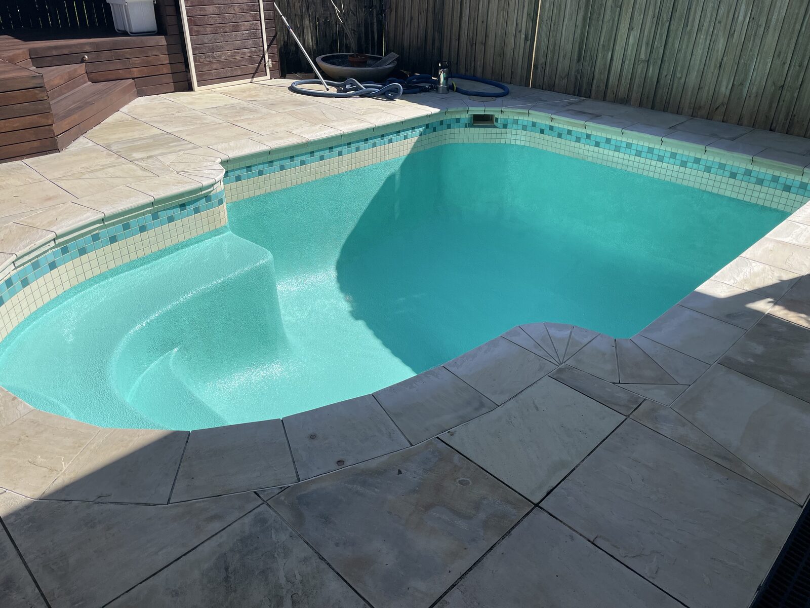Finished pool with teal Luxapool epoxy coating and mosaic tile waterline