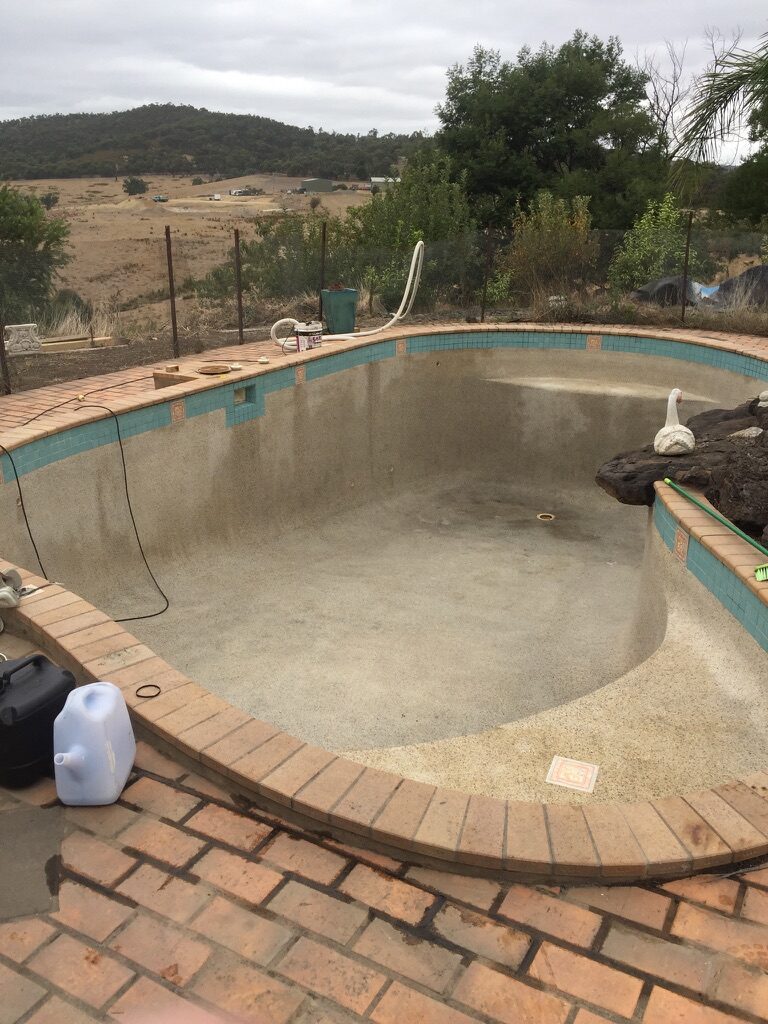 Drained pebblecrete pool on an acreage property before resurfacing